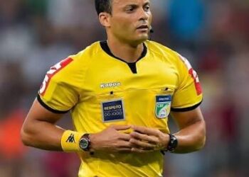 Árbitro de futebol em campo com uniforme amarelo.