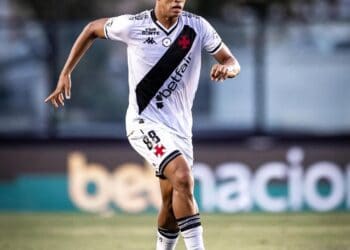 Nike jogador vestindo uniforme do Vasco da Gama em campo, driblando com bola; jogador em ação no estádio.