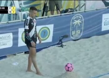 Jovem atleta de beach soccer com bola rosa.