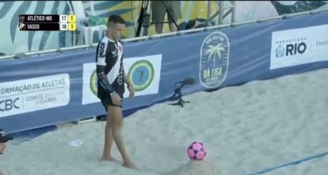 Jovem atleta de beach soccer com bola rosa.