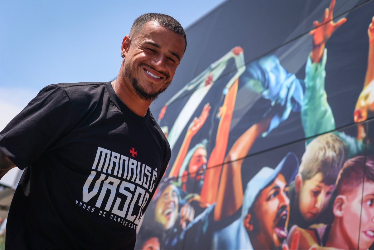 20251024-212418-1-2 Imagem de um torcedor sorridente com camisa preta do Vasco, ao lado de painel colorido com torcedores vibrando.