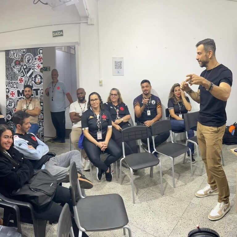 Vasco fan club members listening to speaker in room.