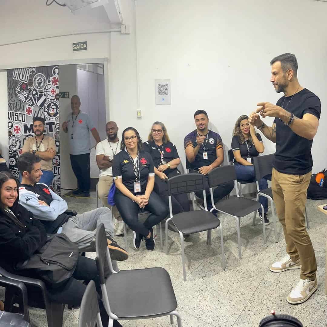 Vasco fan club members listening to speaker in room.