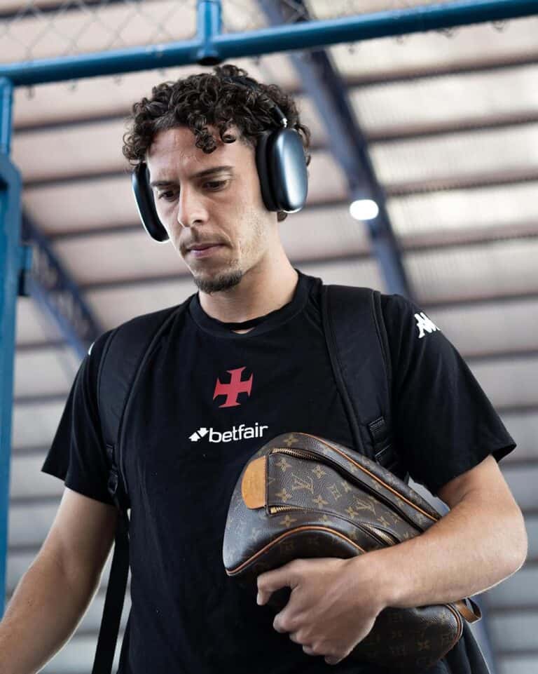 .headphone-wearing man at airport with Louis Vuitton bag.