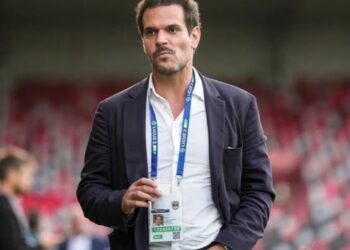 Homem elegante com crachá no estádio.