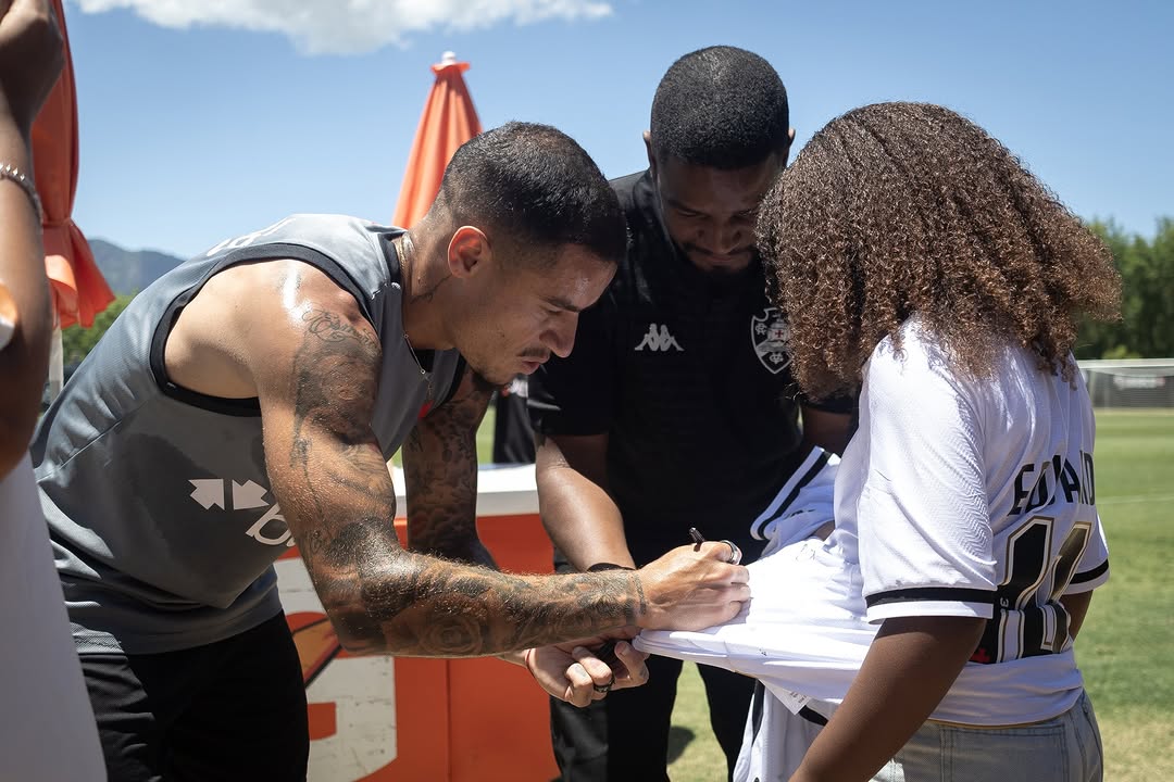 20251027-123555-1-1-1-1 Acompanhe jogadores do Vasco assinando camisa em treino ao ar livre.