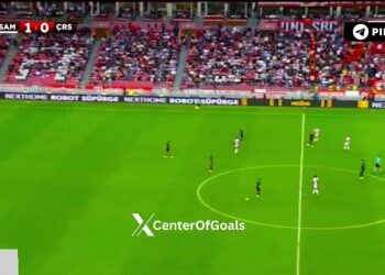 Jogadores em campo durante partida de futebol no estádio.