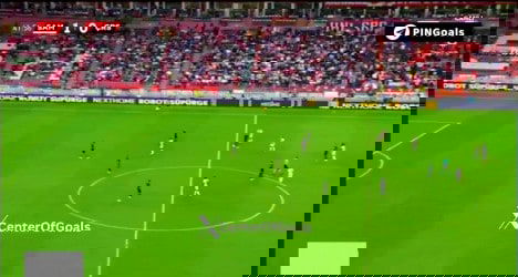 Jogadores em campo durante partida de futebol no estádio.