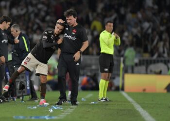 Jogador do Vasco sendo atendido no campo por alguém da comissão técnica.