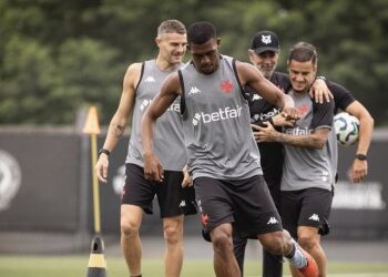 Atleta treinando com bola em campo de futebol.