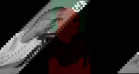 Homem falando em microfone em estúdio.