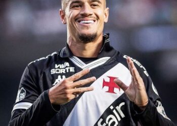 Jogador do Vasco sorrindo com uniforme preto e branco.
