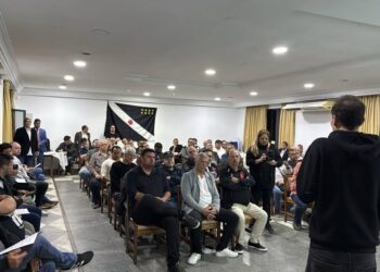 Reunião de torcedores do Vasco com público diverso em ambiente interno, alguns participantes estão usando camisetas com homenagem ao time.