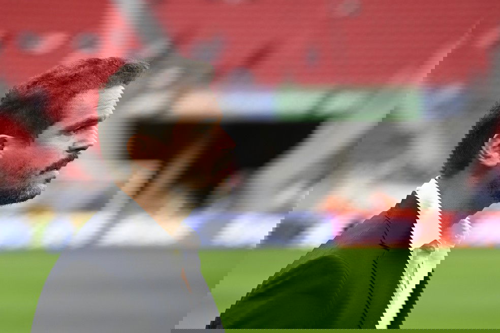 20251101-130501-1-10-admar-lopes-executivo-de-futebol-do-vasco-foto-mateus-bonomiagif Fotógrafo em estádio com homem de terno ao lado do campo, pensando.