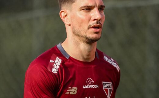 Vasco jogador de futebol em campo com uniforme vermelho.