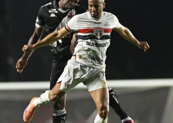 Jogadores de futebol em ação durante partida noturna.