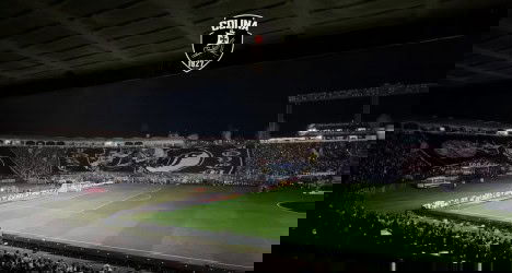 Estádio de futebol lotado à noite.