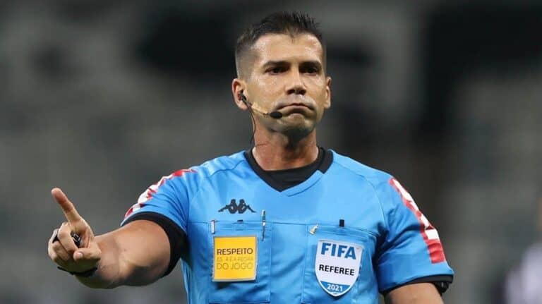 Árbitro de futebol com uniforme azul e microfone.