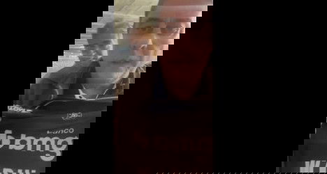 Homem falando ao celular com fundo de pessoas.