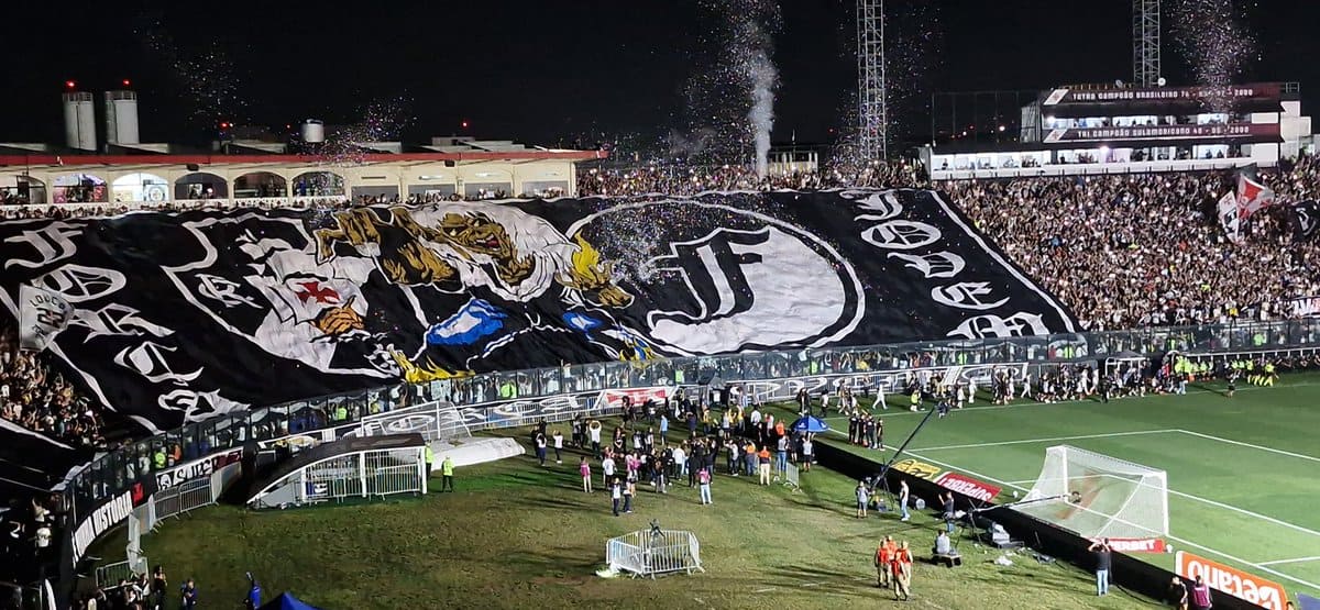 Vasco da Gama torcedor com bandeira gigante no estádio.
