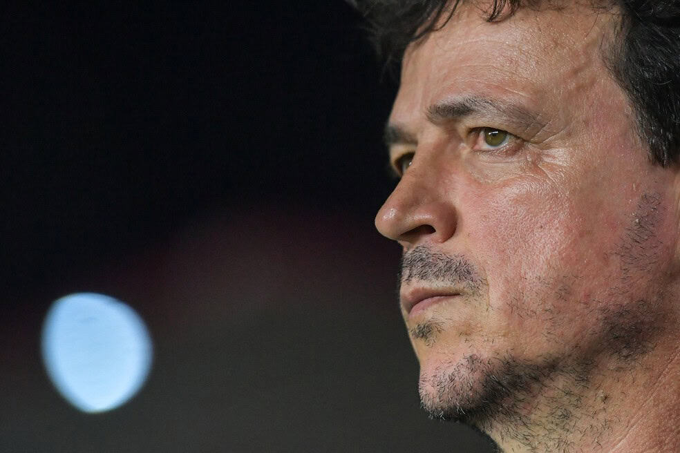 Fotografia de um homem observando atentamente, com expressão séria e focada, com fundo escuro.