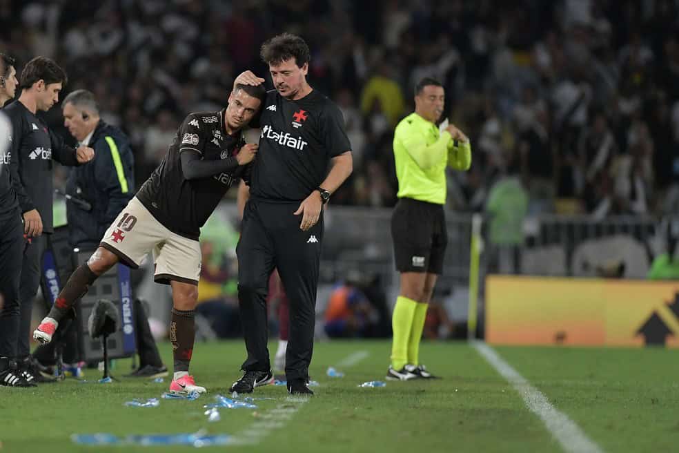 Jogador do Vasco sendo consolado por treinador na beira do campo.
