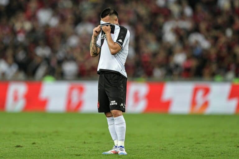 Chorando e cobrindo o rosto com a camisa.