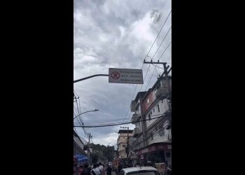 Táxi parado na rua com prédio ao fundo e avisos de trânsito.