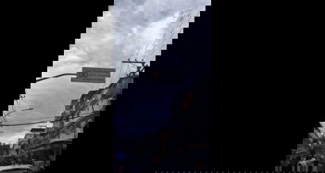 Táxi parado na rua com prédio ao fundo e avisos de trânsito.