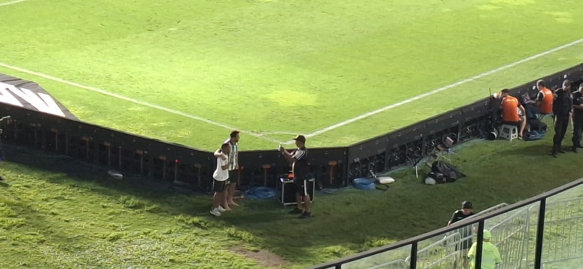 Estádio de futebol com técnicos e equipe de suporte.
