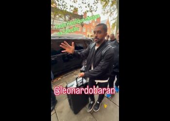 Homem sentado na calçada, gesticulando.