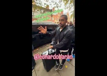 Homem sentado na calçada, gesticulando.