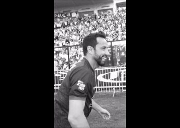 Atleta comemorando com sorriso no estádio.