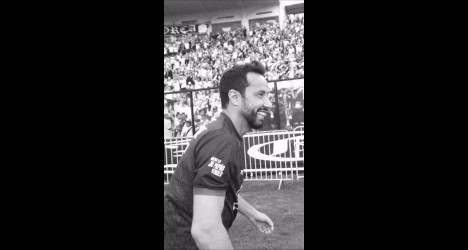 Atleta comemorando com sorriso no estádio.