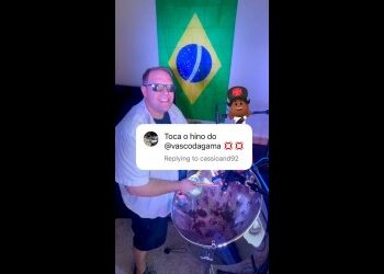 Homem sorrindo com bandeira do Brasil ao fundo.