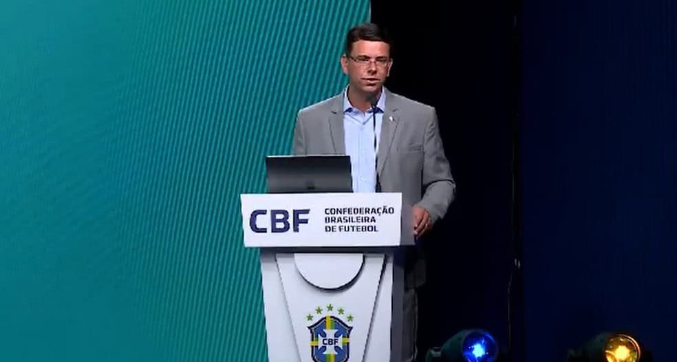 CBF, conferência de futebol, homem em palestra, palco com logo, apresentação esportiva.