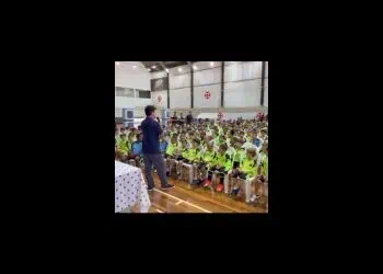 Alto risco de concurso: crianças com uniformes amarelos e adultos presentes em evento escolar.