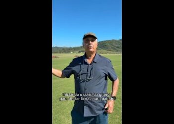 Homem segurando régua no campo.