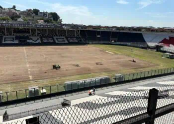 Linha de fundo: Estádio do Vasco com gramado em reforma e arquibancadas vazias.