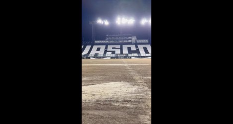 Estádio de futebol vazio com iluminação ao fundo.