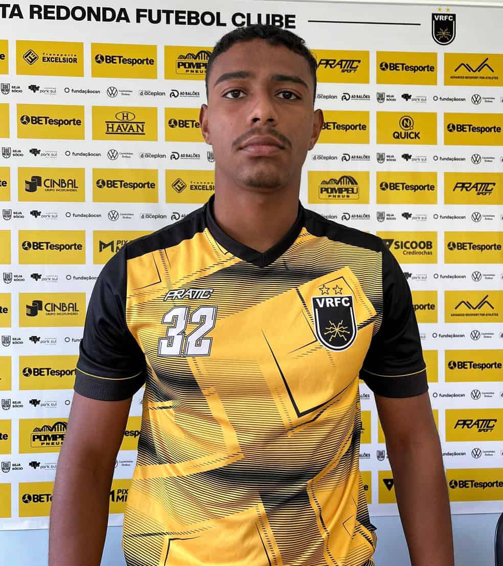Jogador com uniforme do Vasco em fundo de patrocinadores.