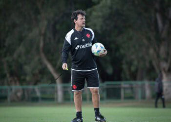 Treinador com bola de futebol no campo.