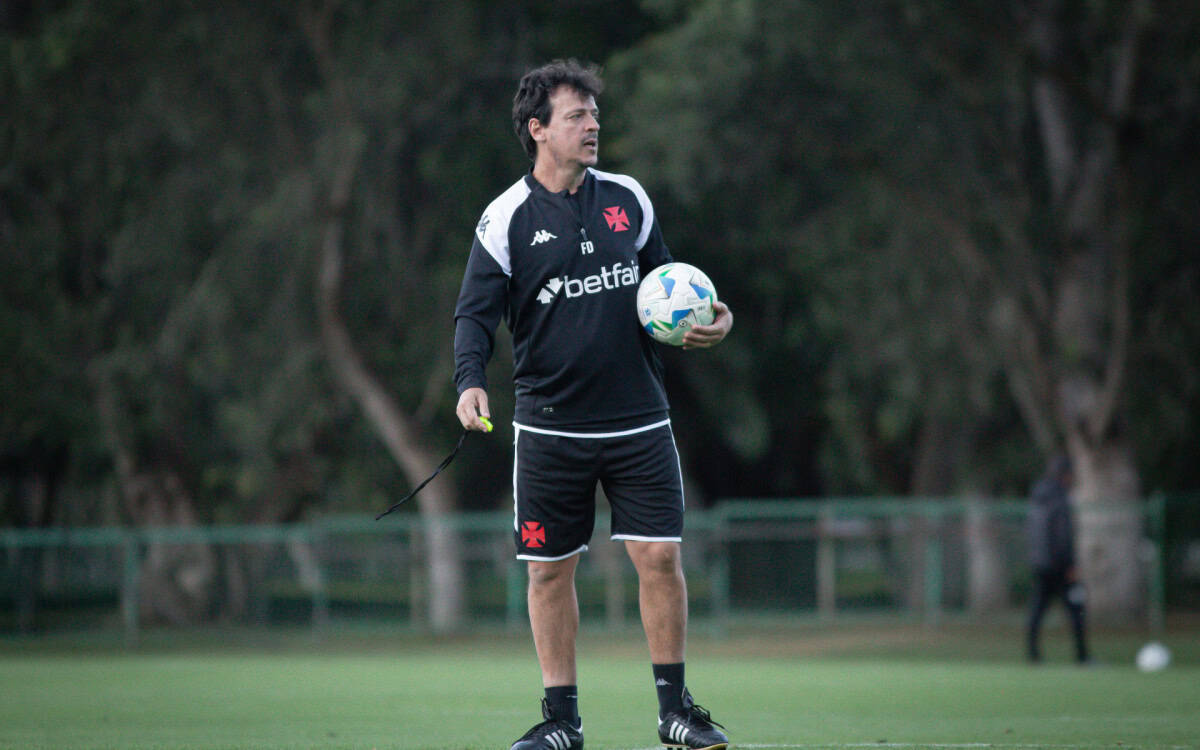 Treinador com bola de futebol no campo.