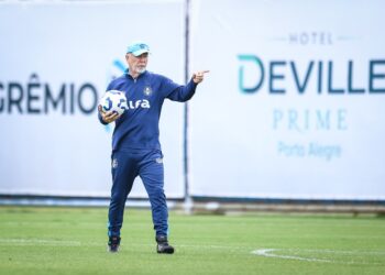 Treinador de futebol com bola em campo.