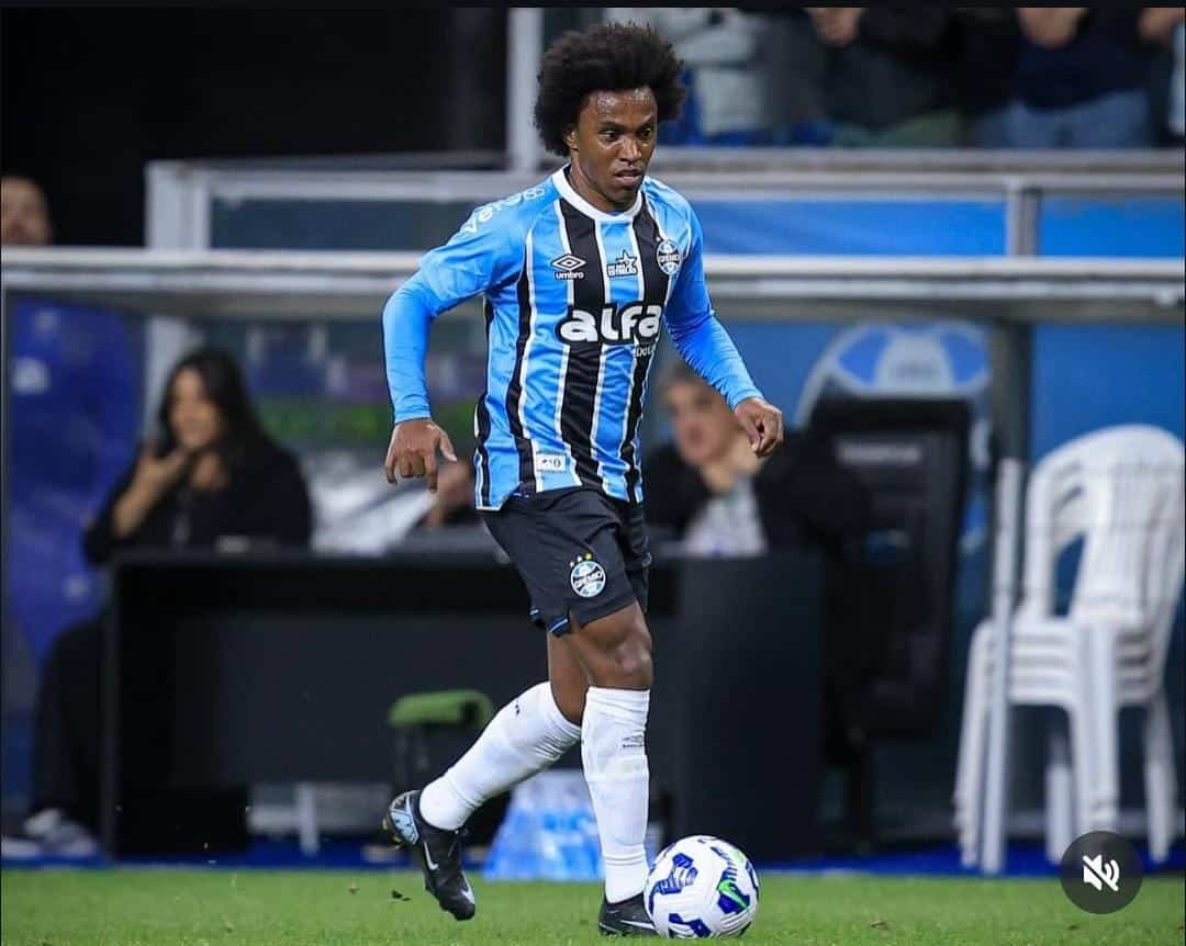 Jogador de futebol em campo, driblando a bola.