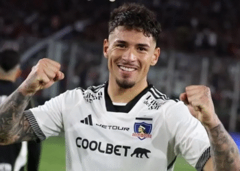 Jogador comemorando vitória com sorriso e punhos fechados.