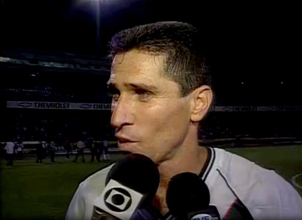 Jogador de futebol com cabelo curto e camisa branca.