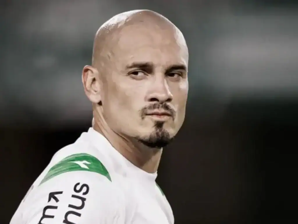 Cabelos raspados e expressão séria.