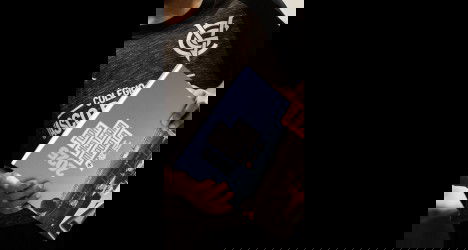 Aluno segurando caderno e smartphone na escola.