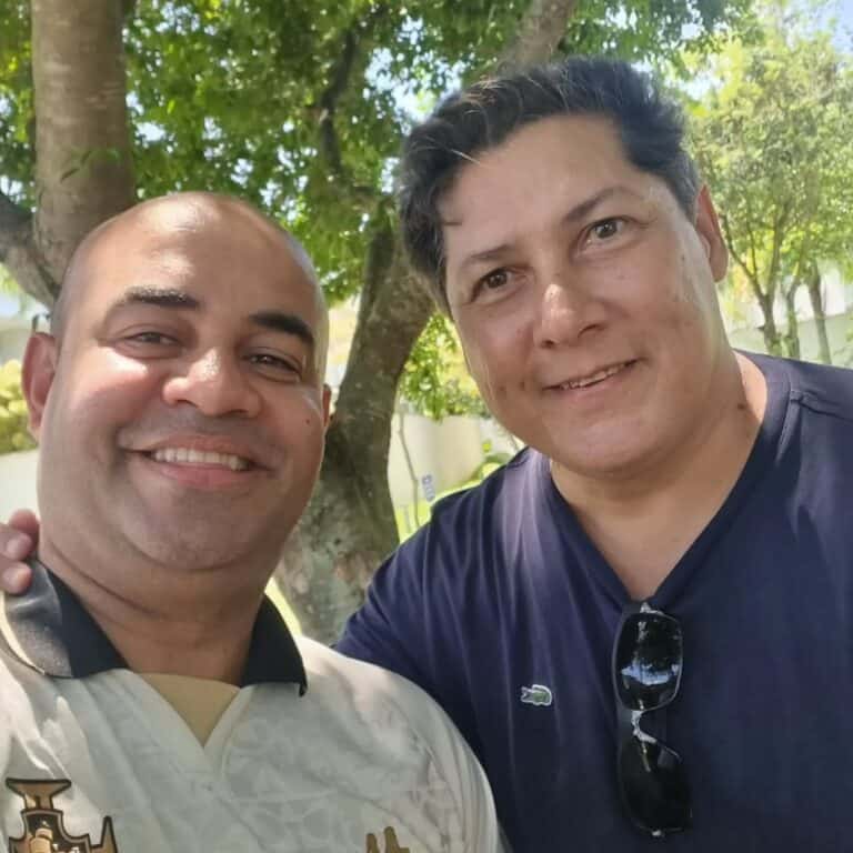 Homem sorrindo em ambiente ao ar livre.